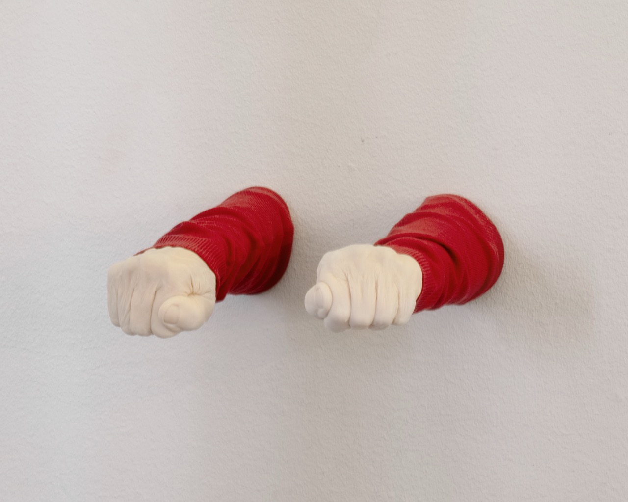 Artwork of two fists in red sleeves emerging from a white wall