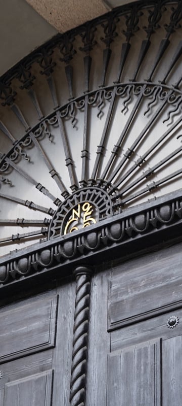 Wrought-iron gate with a gold medallion numbered 65 at Sveavägen 65