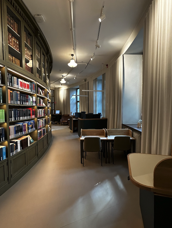 Library entrance with desks, bookshelves and tall curtains